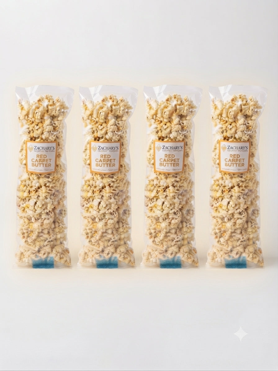 Four clear plastic bags of ZACCHUS RED CARAMEL BUTTER popcorn arranged in a row on a light gray background.