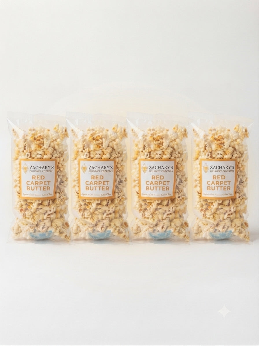 Four clear plastic bags of Zachary's Red Carpet Butter popcorn arranged in a row on a clean white background.