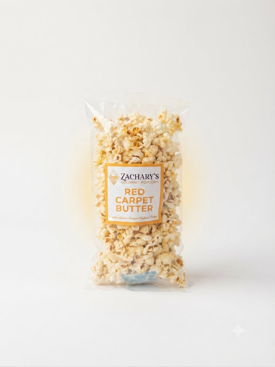 A clear plastic bag of Zachary's Red Carpet Butter popcorn, showing the golden-brown popcorn kernels inside with a white and orange label, set against a clean white background.